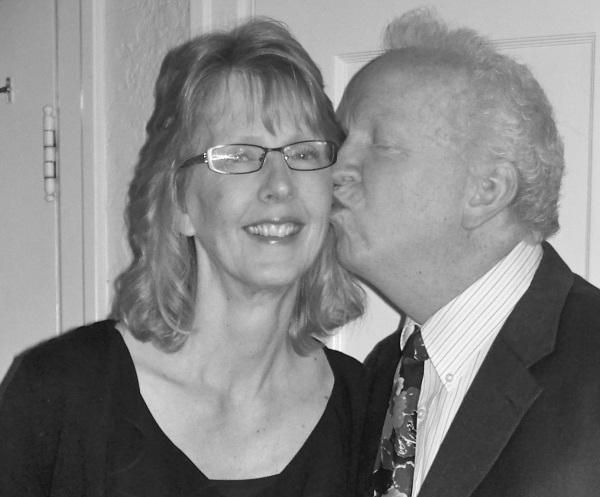 Photo from the 2012 Christmas letter: a black-and-white photo of a smiling woman with glasses being kissed on the cheek by an older man