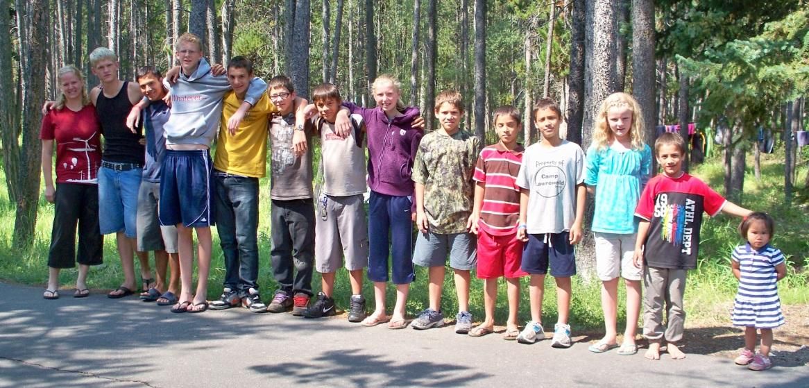 Photo from the 2012 Christmas letter: a long line of children standing together on a forest road