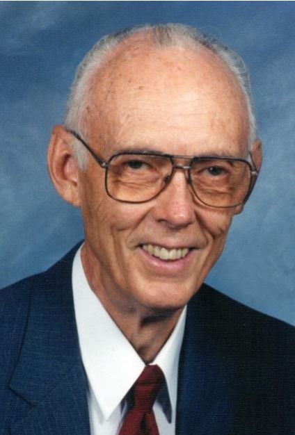 Photo from the 2018 Christmas letter: Grover Rose, smiling, in glasses, a blue jacket and a red tie